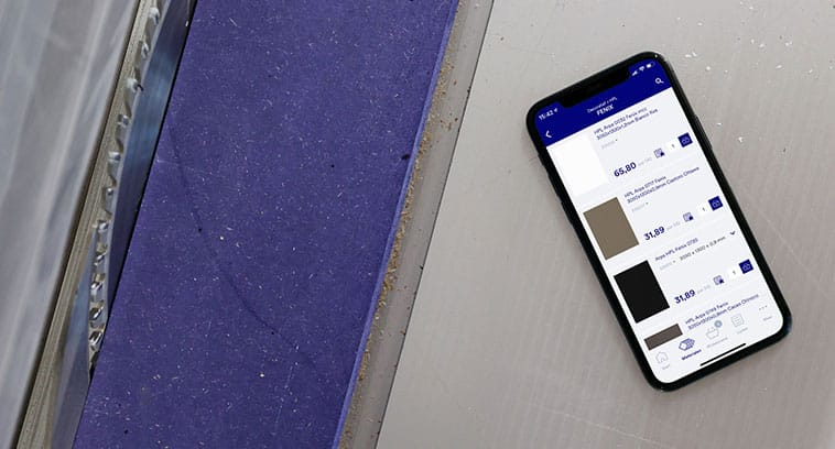 Smartphone met de Baars & Bloemhoff app geopend, liggend op een zaagmachine